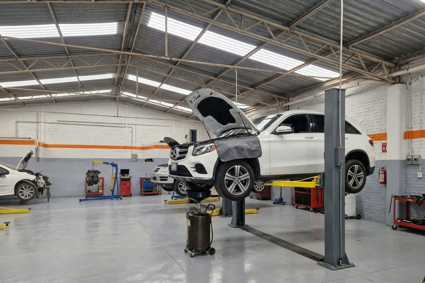 Mercedes-Benz GLC blanco sobre un elevador con el cofre abierto