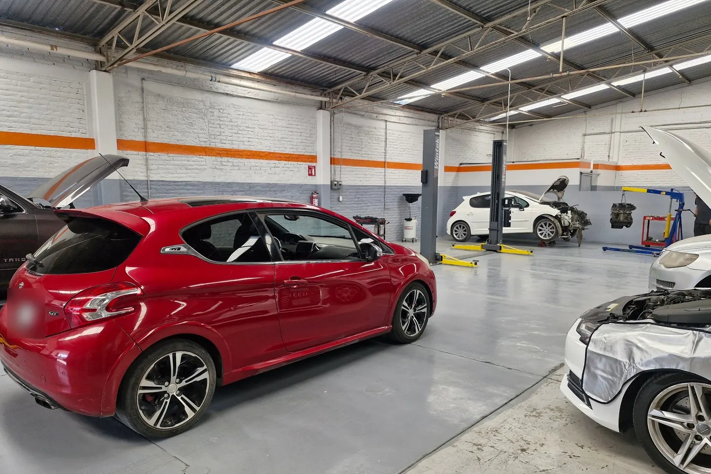 Vista amplia del área de trabajo del taller Motorfix, con elevadores y autos en servicio