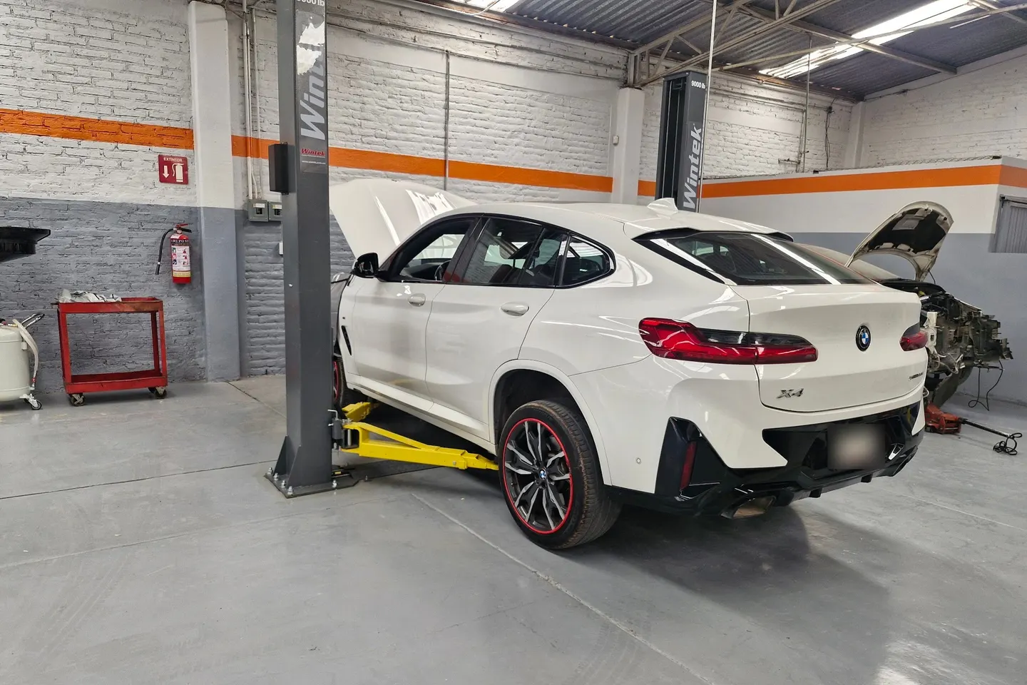 BMW X4 blanco sobre un elevador en el taller Motorfix